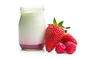 yogurt in jar with strawberries and raspberries on white background